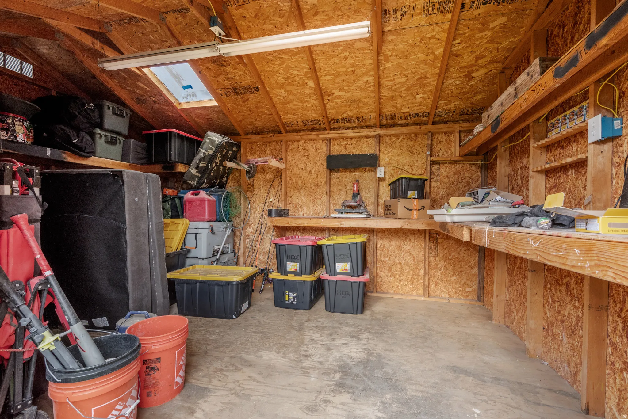 Utility shed featuring exposed wood framing, built-in workbench, and overhead shelving