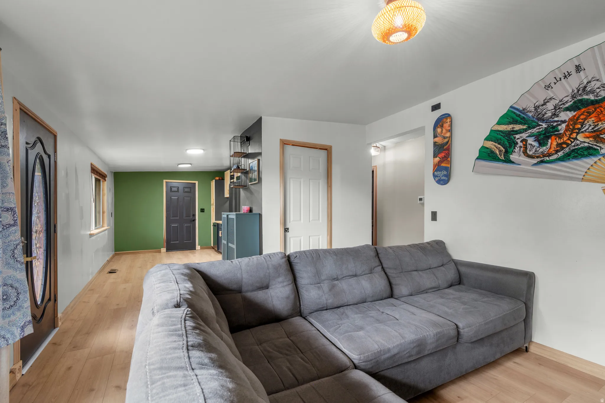 Open-concept living space featuring wood-finish flooring, recessed lighting, and a prominent green accent wall