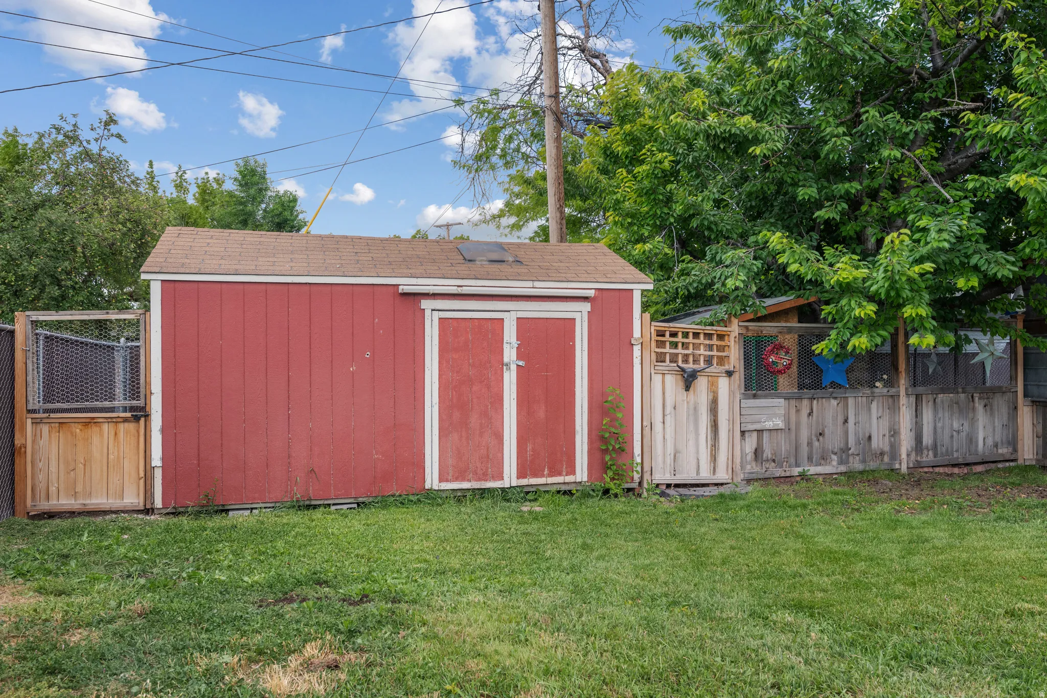 Red storage shed featuring double doors and a shingled roof
