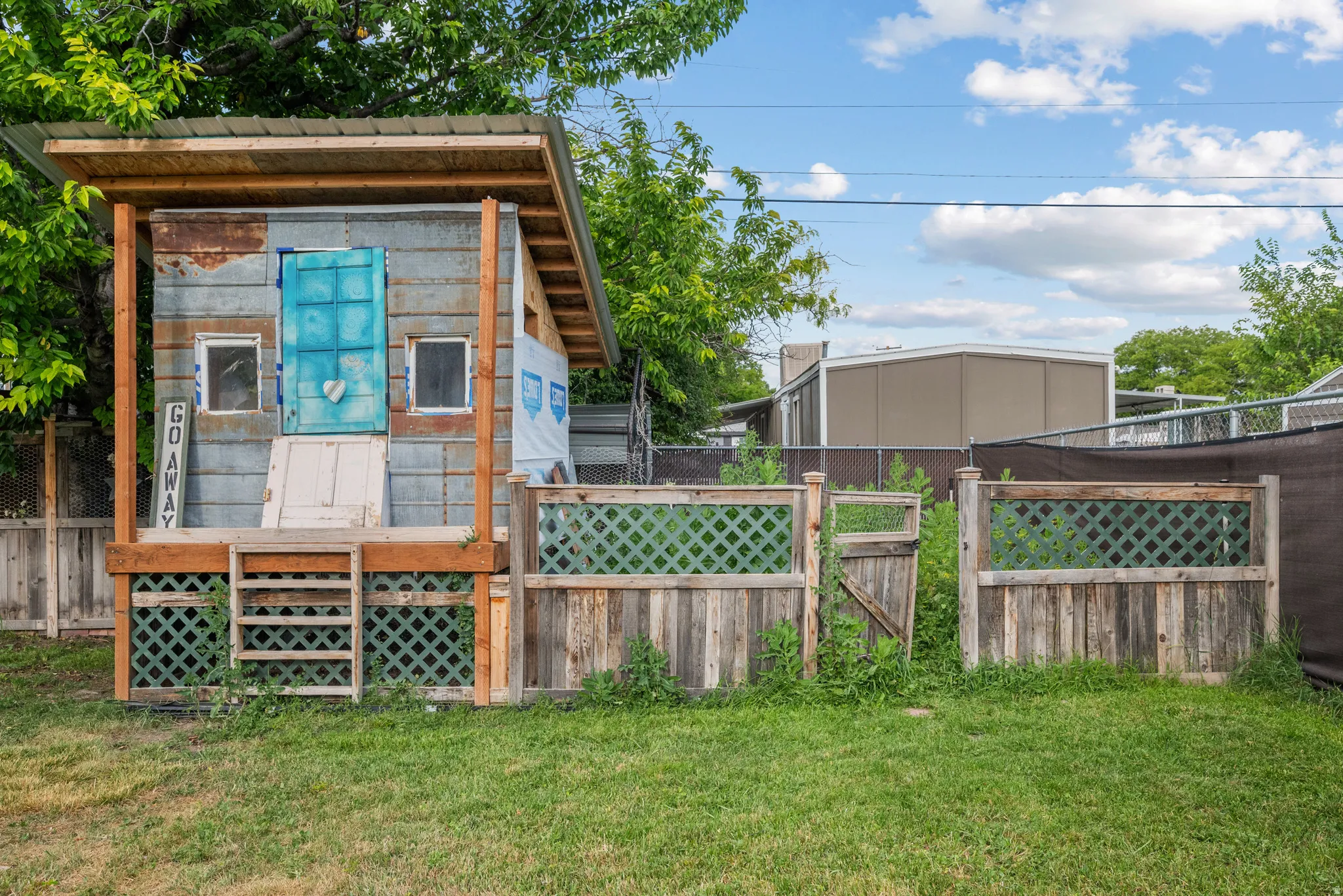 Detached backyard structure with a metal roof, elevated wooden deck, and wooden lattice detailing