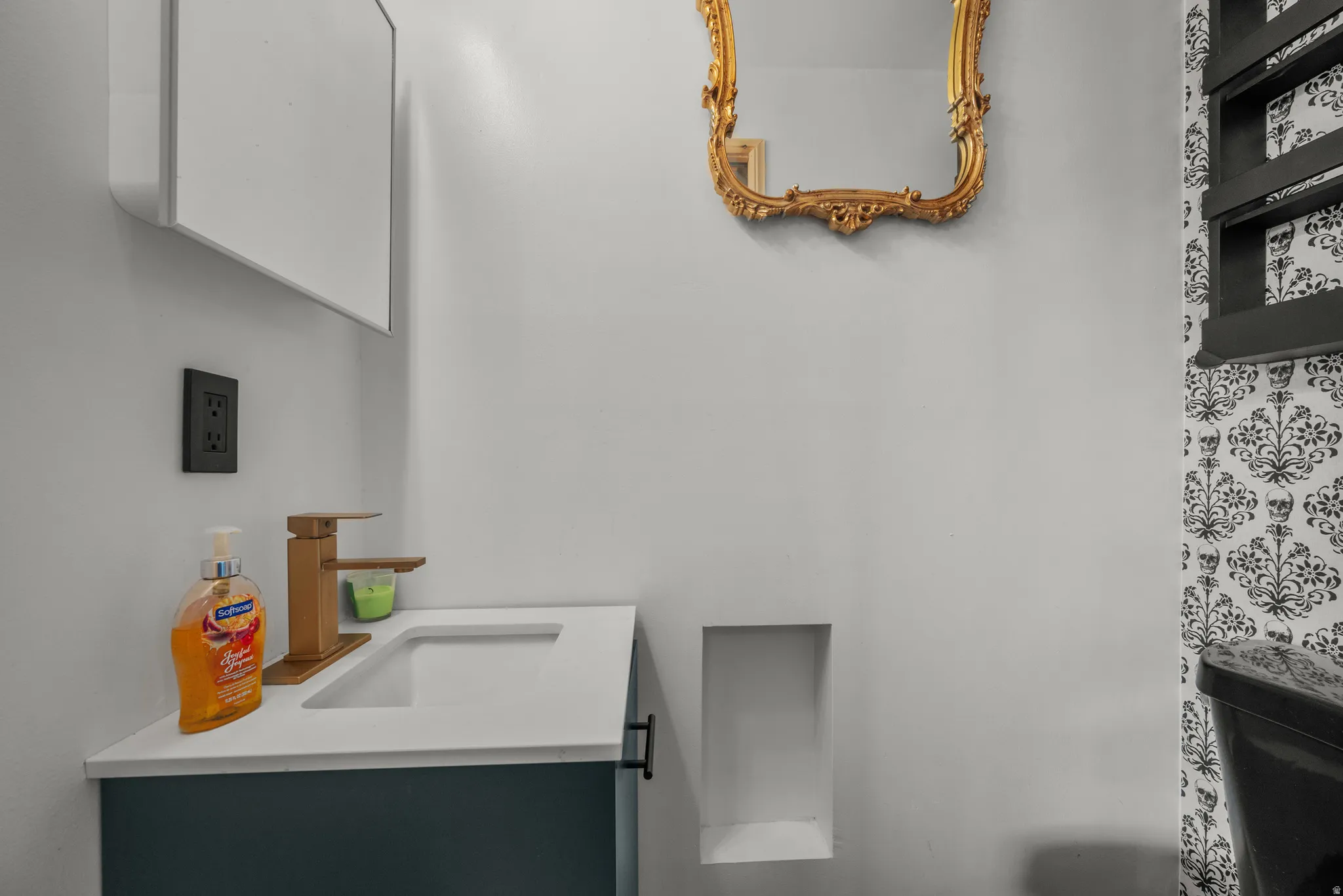 Contemporary vanity featuring a white countertop with integrated sink and a gold-toned faucet