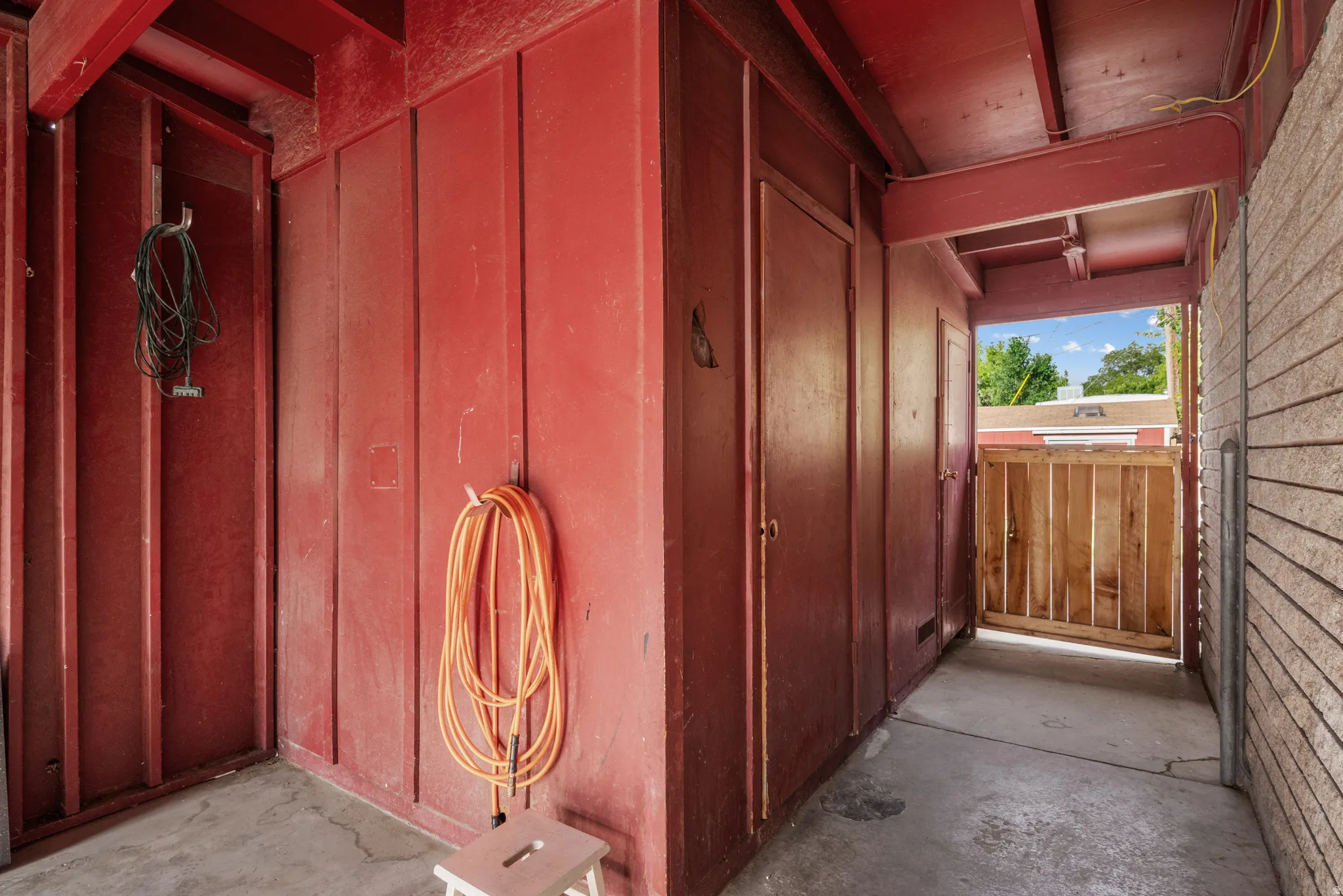 Covered outdoor passage featuring vertical wood paneling in a deep red finish
