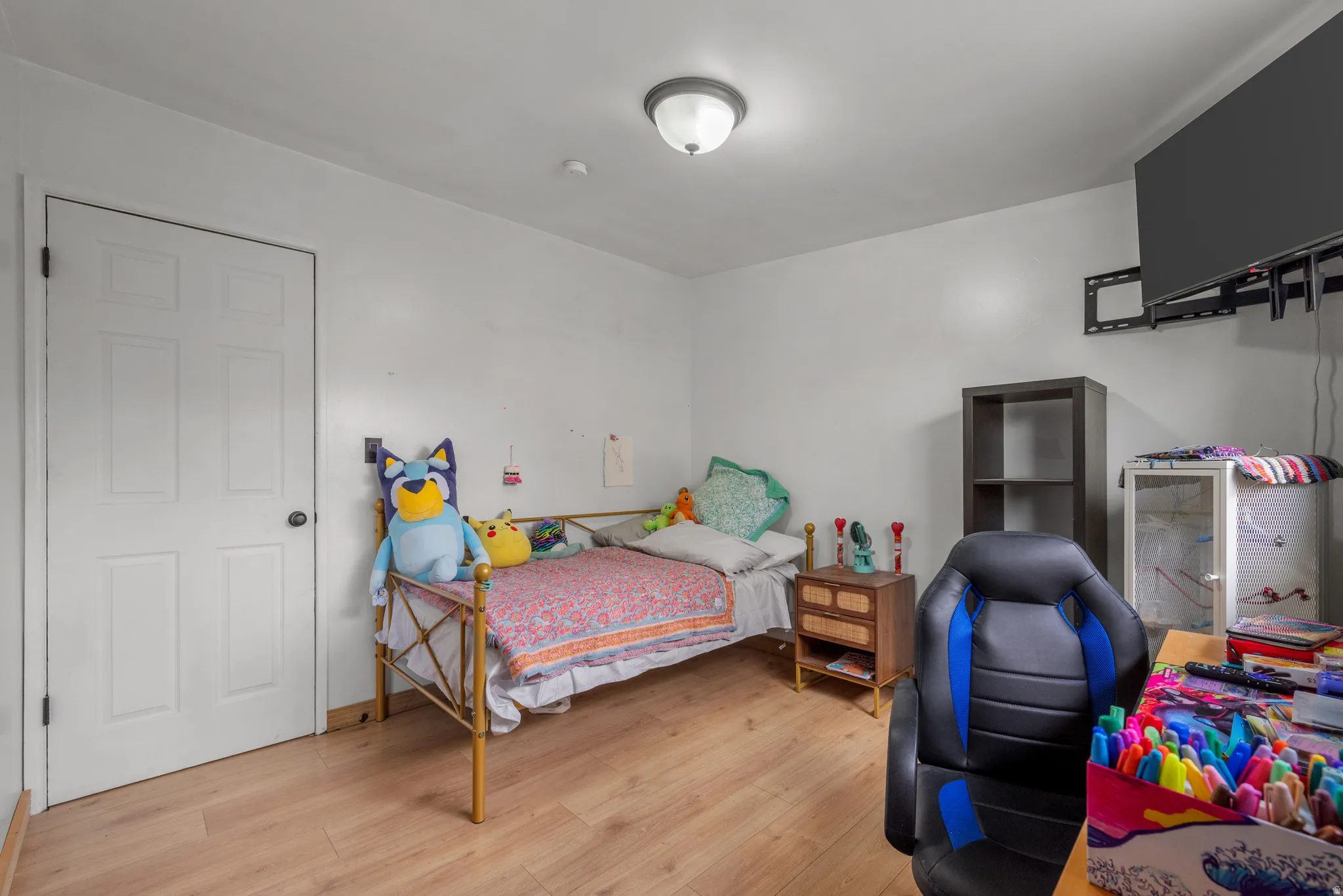 Bright room featuring light wood-finish flooring, white walls, a white six-panel door, and a flush-mount ceiling light fixture