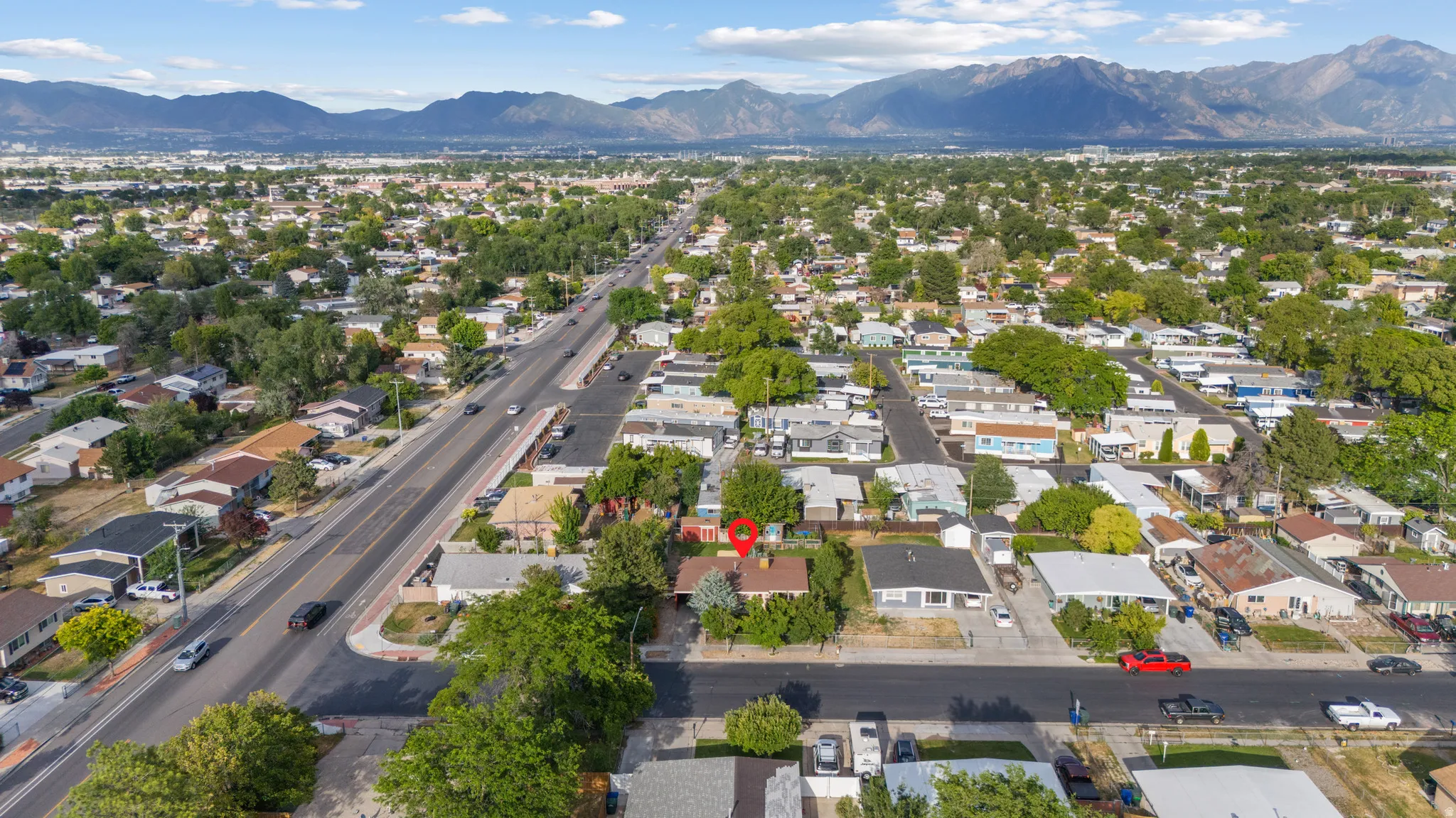 Aerial perspective showcasing a residential area with mature trees and mountain ranges in the background