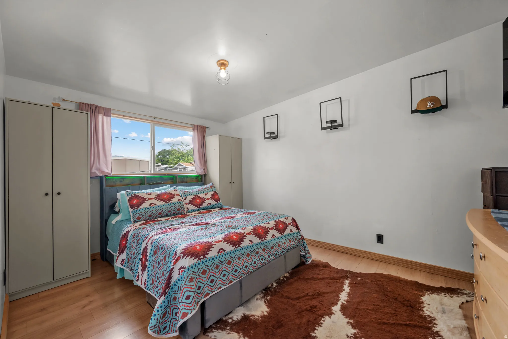 Bedroom featuring wood-finish flooring, a large window, and light-toned walls