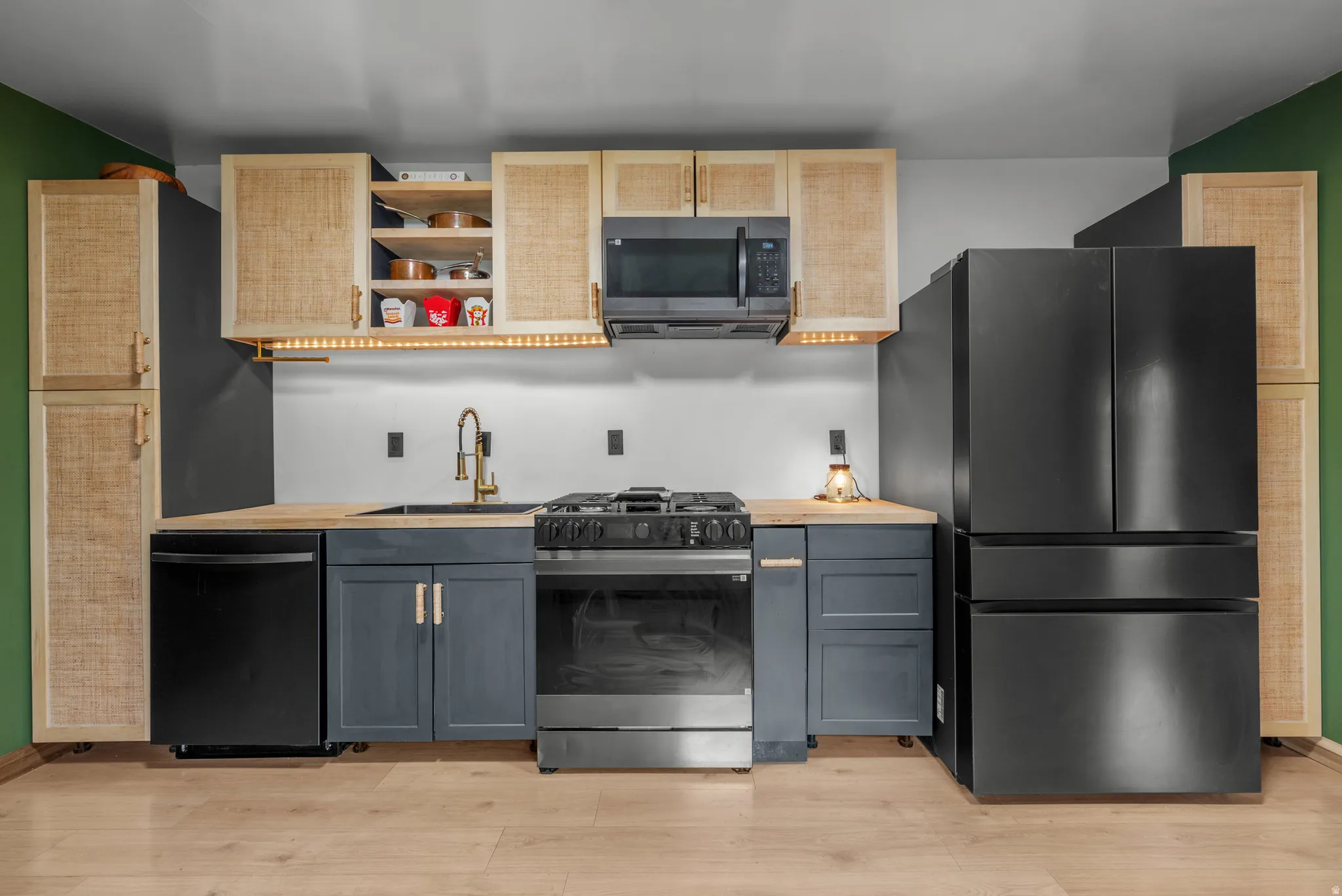Efficient kitchen featuring dark-toned appliances including a gas range, dishwasher, microwave, and refrigerator