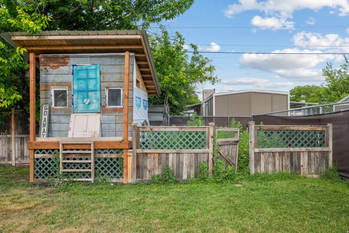 Detached backyard structure with a metal roof, elevated wooden deck, and wooden lattice detailing