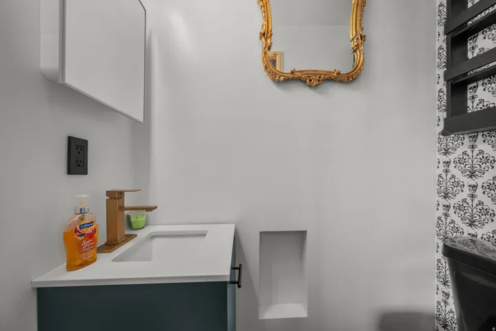 Contemporary vanity featuring a white countertop with integrated sink and a gold-toned faucet