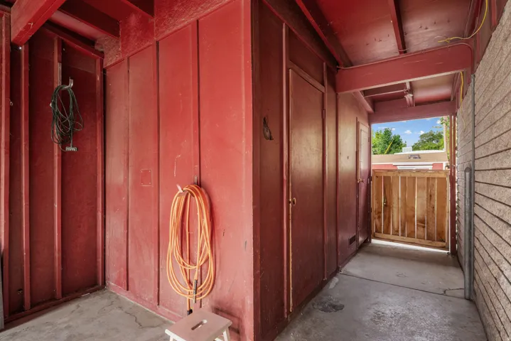 Covered outdoor passage featuring vertical wood paneling in a deep red finish