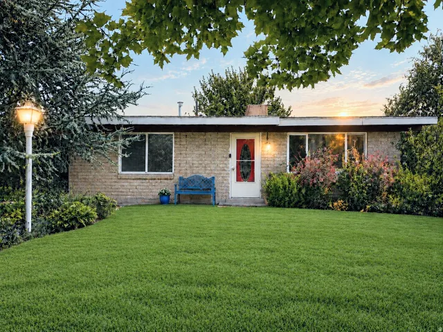 Brick exterior with a white entry door, an exterior wall lantern, and a manicured front lawn