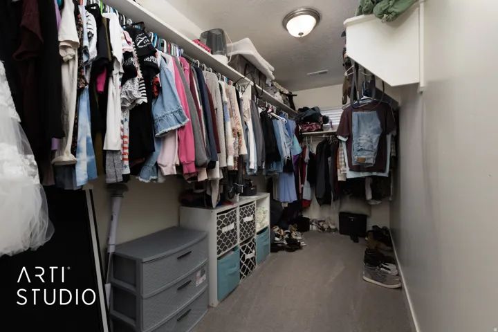 Expansive walk-in closet featuring built-in shelving, multiple hanging rods, durable carpeting, and a flush-mount ceiling light fixture