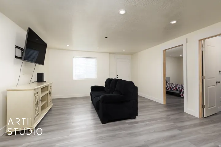 Spacious living area featuring wood-finish flooring, recessed lighting, and a window with blinds