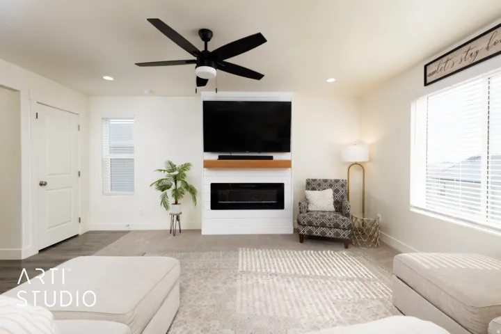 Living area featuring a floor-to-ceiling media wall with integrated electric fireplace and wood mantle