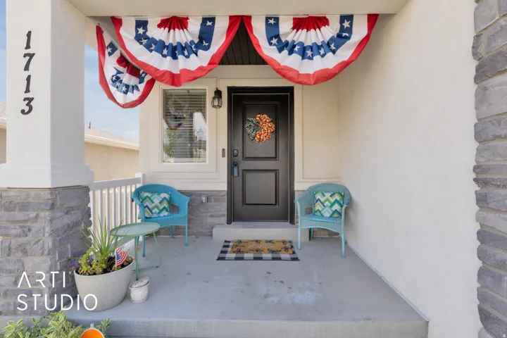 Inviting front porch featuring a dark entry door, a single window, and stone column detailing