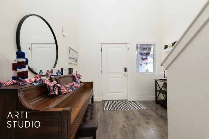 Entryway featuring wood-finish flooring, a white door with dark hardware, and a high ceiling