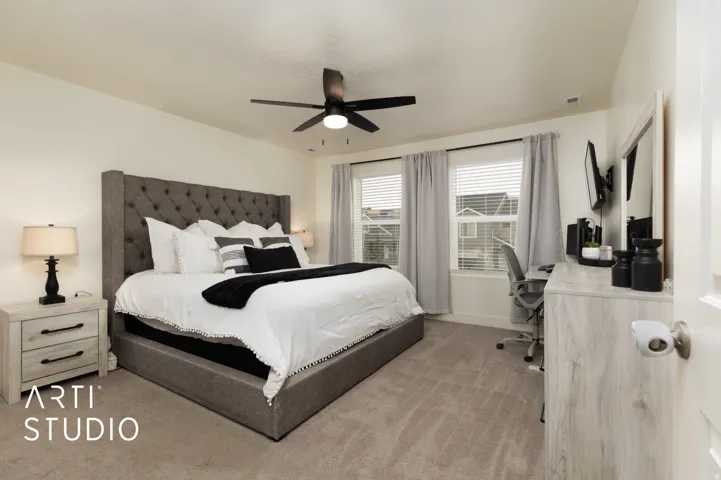 Carpeted room featuring a ceiling fan with integrated lighting, two windows with blinds and drapes, and a white interior door with a brushed nickel knob