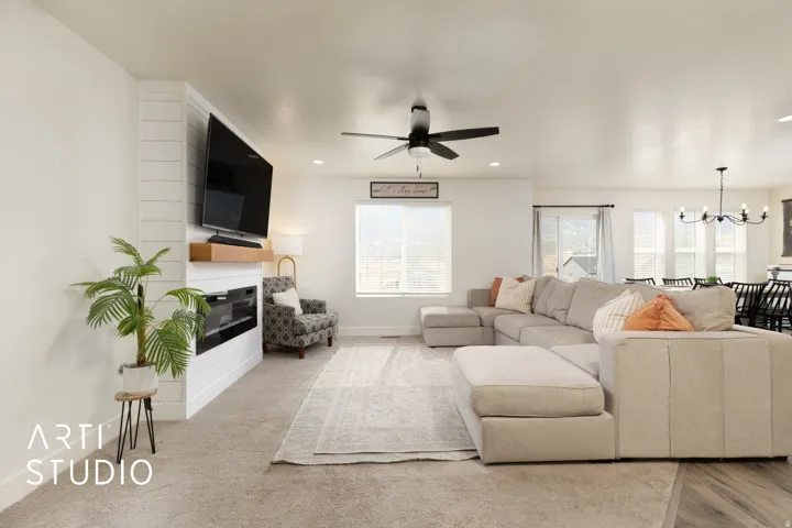 Open-concept living space featuring a shiplap accent wall with a built-in electric fireplace and a wood mantel