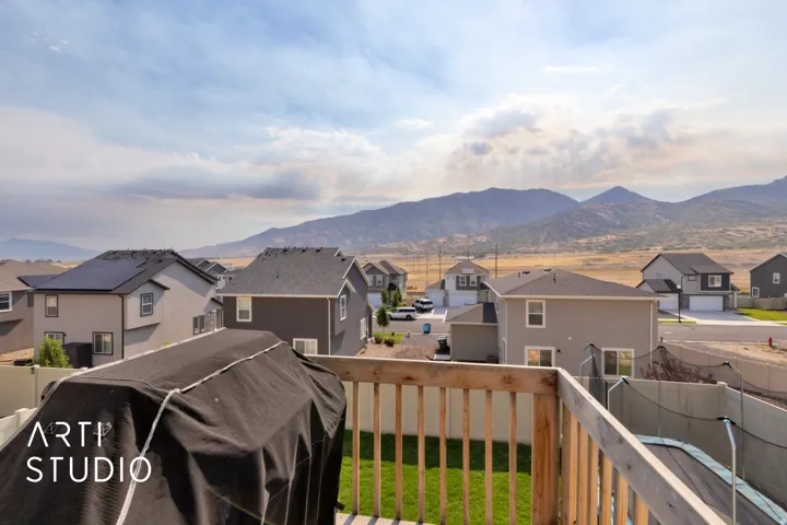 Wood railing on an upper-level deck overlooking a residential area with mountain scenery