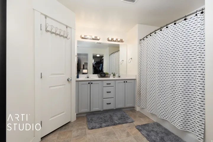 Bathroom featuring a dual vanity with light gray cabinetry, a white countertop, and a large mirror