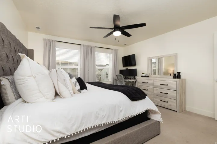 Spacious bedroom featuring light-colored walls and soft carpeting