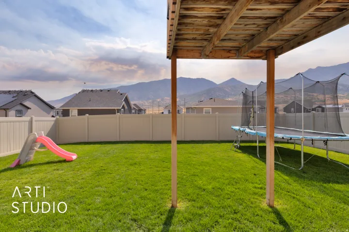Expansive backyard featuring a green lawn, privacy fencing, and a mountain backdrop