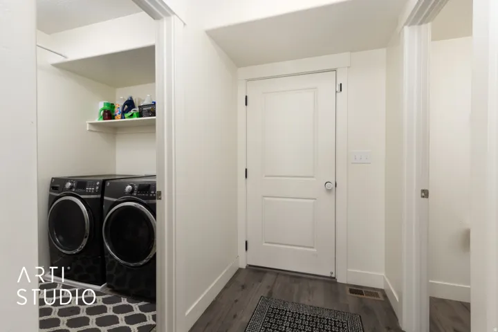 Dedicated laundry area featuring built-in shelving, wood-finish flooring, and crisp white trim