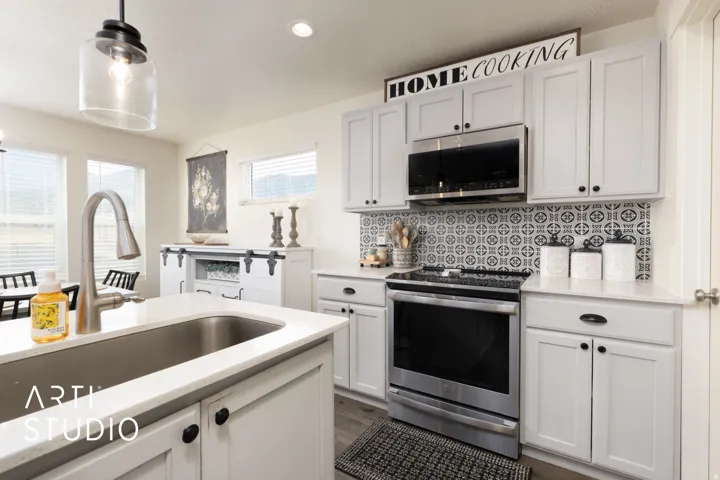 Contemporary kitchen featuring light gray cabinetry, stainless steel appliances, and a patterned tile backsplash