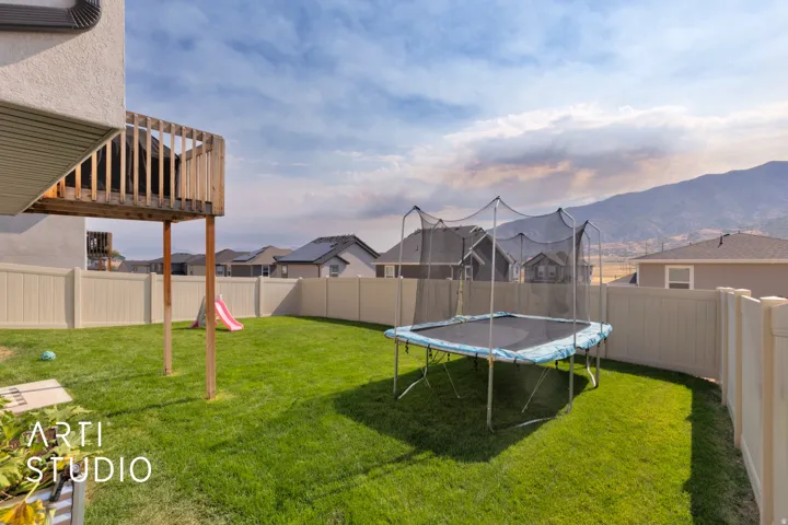 Expansive backyard featuring a manicured lawn, a full-height privacy fence, and a wooden elevated deck structure