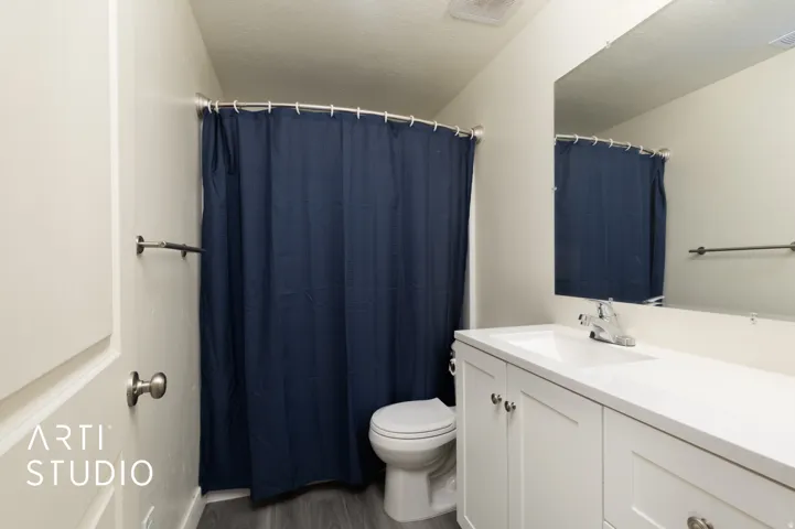 Bathroom featuring a white vanity with integrated sink, chrome faucet, white flat-panel cabinetry, and wood-finish flooring