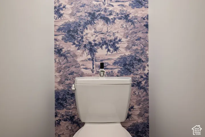 Private water closet featuring a simple, refined design and a distinctive wallpaper accent wall.