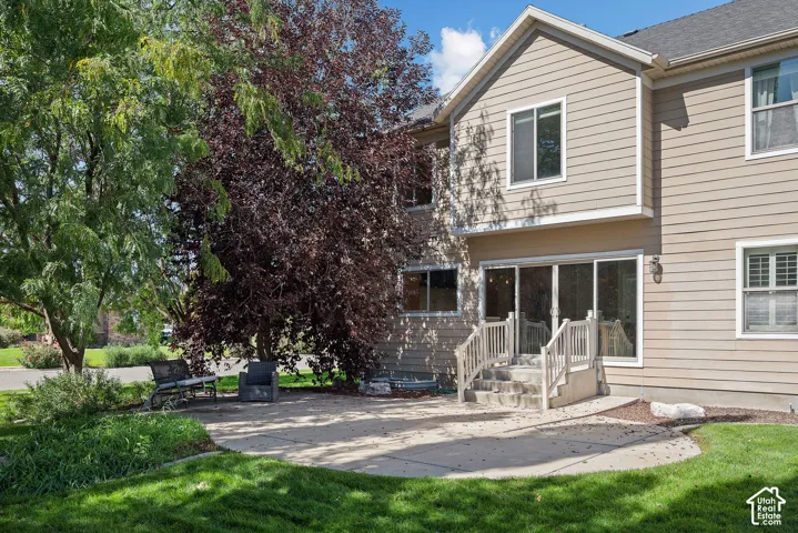 Private, maturely landscaped backyard framed by established trees and featuring a curved concrete patio for outdoor seating and gathering.