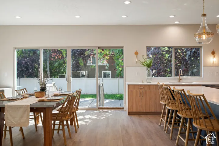 A kitchen surrounded by windows brings in natural light throughout the day, while mature trees provide shade and a beautiful view as the evening unfolds