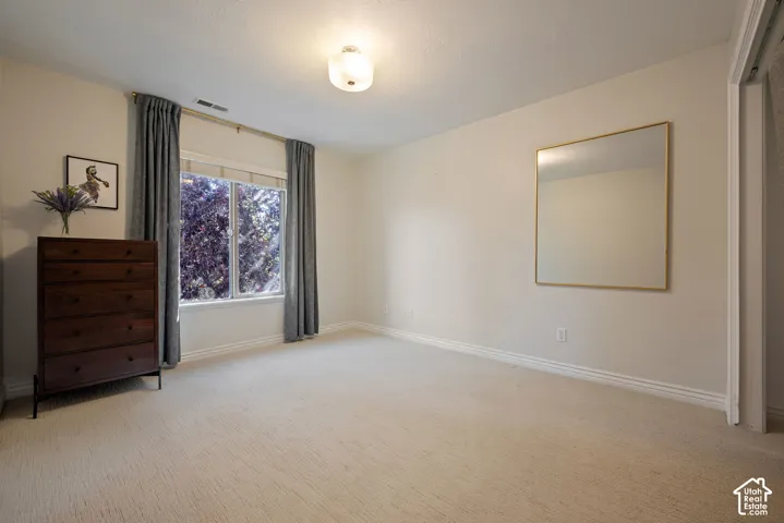 Second-floor bedroom with neutral walls, quality carpet, and beautiful treetop views through the window.
