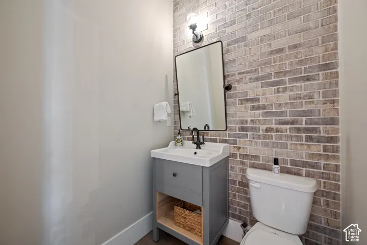Cleverly positioned half bath just off the kitchen and gathering areas. A brick-and-mortar accent wall adds character, while the transom window brings in natural light.