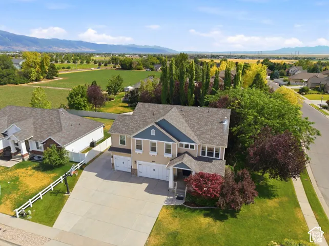 Two-story residence featuring a three-car garage, pitched roof, and mature landscaping