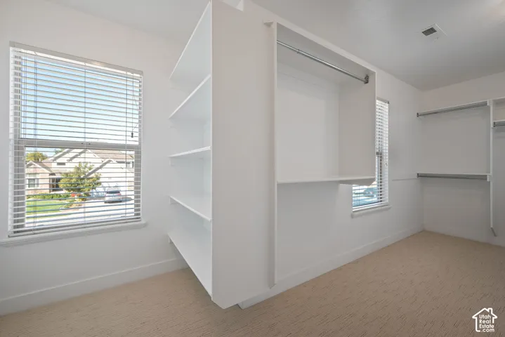 A rare primary closet with windows, natural light, and a thoughtful layout that provides exceptional room for clothing, dressing, and organization.