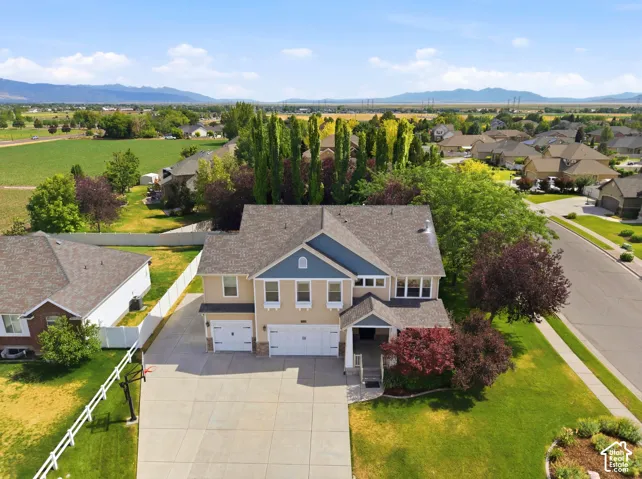 Two-story residence featuring a three-car garage, established landscaping, and a paved driveway