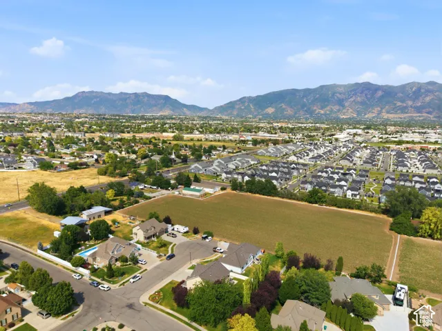 Aerial perspective with expansive mountain backdrop, showcasing a residential neighborhood, green spaces, and community development
