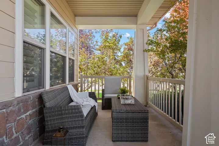 This covered front porch creates an intimate outdoor living, secluded by groomed trees and shrubs in a cozy space.