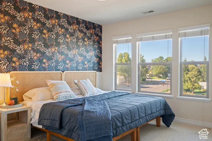 Second view of the generously proportioned bedroom, showcasing its flexible furniture arrangement and natural light.