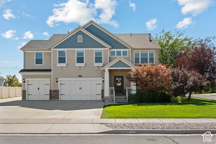 Two-story Craftsman with three insulated carriage-style garage doors, additional parking for 7+ vehicles, and mature trees and landscaping that provide an established, welcoming setting.
