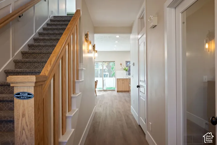 View from the front entry featuring a solid modern wood staircase, carpet runner, two-tone trim, and a transom window that brings additional light into the foyer.