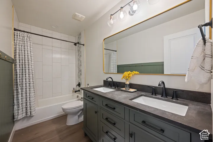 Shared full bath with dual sinks, solid-surface soapstone countertop, black fixtures, modern lighting, and floor-to-ceiling tile.