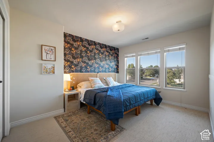 Inviting bedroom comfortably accommodates a king-size bed, with three windows providing abundant natural light and a removable wallpaper accent wall adding personality.