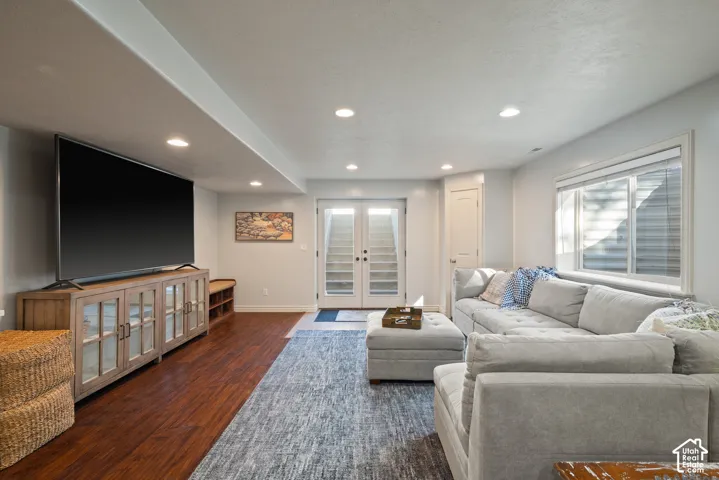 Bright, airy basement living room featuring a large window and French doors opening to wide walk-out stairs and the outdoors.