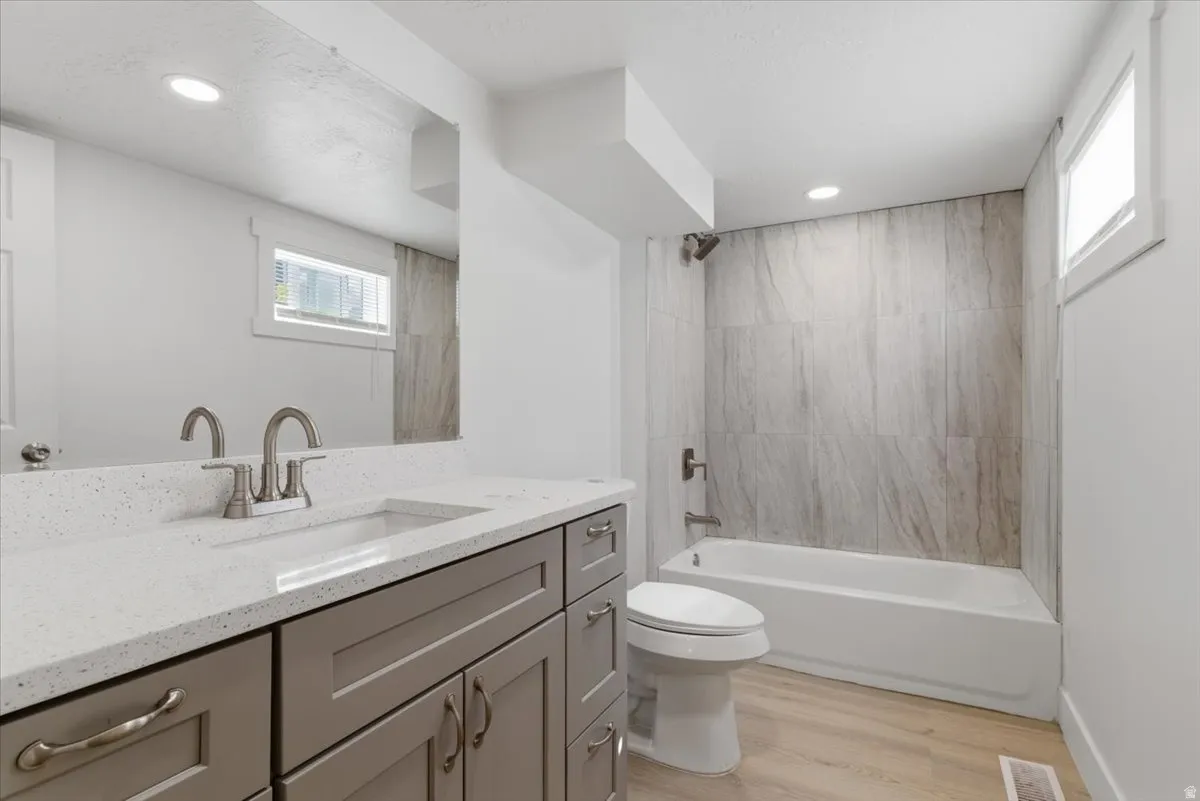 Bathroom featuring a single vanity with grey cabinetry, a light-colored solid surface countertop, and a rectangular undermount sink with brushed nickel fixtures