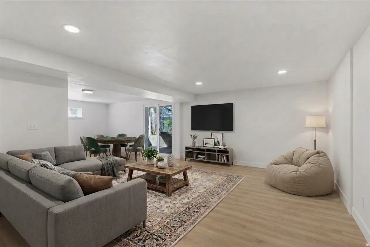 Spacious living area featuring light wood-finish flooring, recessed lighting, and a neutral color palette