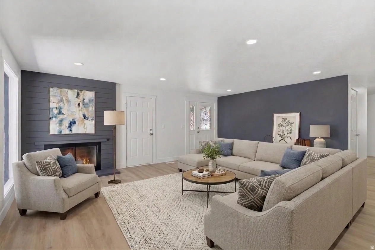 Living room featuring wood-finish flooring, a fireplace with dark shiplap surround, white trim throughout, and recessed lighting