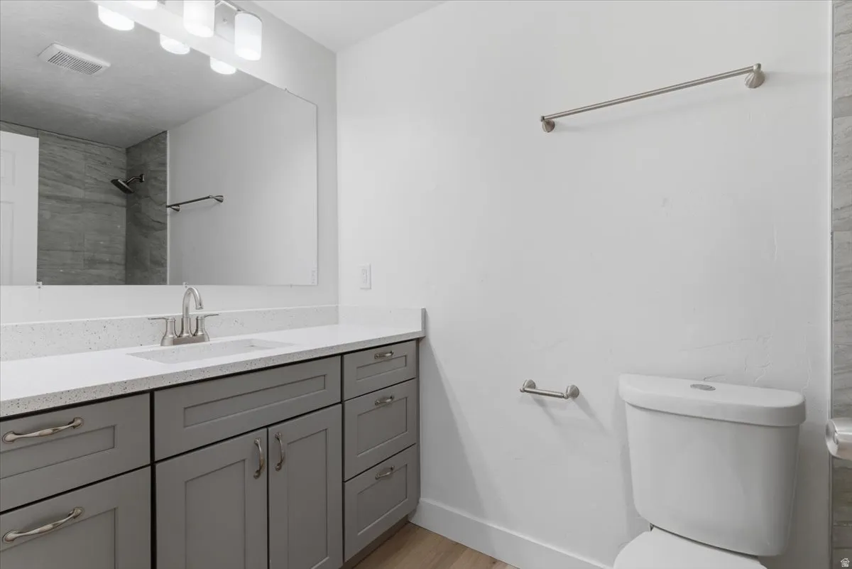 Contemporary bathroom featuring a long vanity with gray shaker-style cabinetry, a white countertop, and an integrated sink