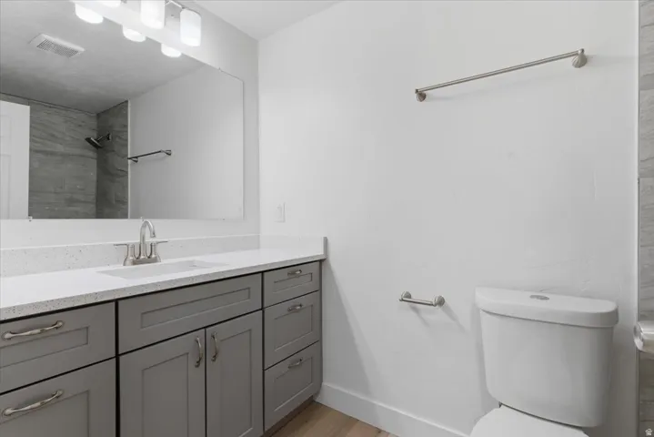 Contemporary bathroom featuring a long vanity with gray shaker-style cabinetry, a white countertop, and an integrated sink